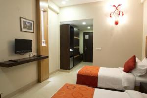 Habitación de hotel con cama y TV en Hotel The Amaris, en Rishīkesh