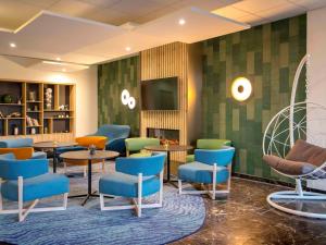a waiting room with chairs and tables and a tv at Mercure Cavaillon in Cavaillon