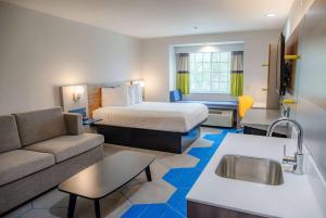 Habitación de hotel con cama y sofá en Microtel Inn & Suites by Wyndham Kingsland Naval Base I-95, en Kingsland