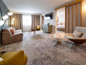 a living room with a couch and chairs and a bed at Mercure Bordeaux Lac in Bordeaux