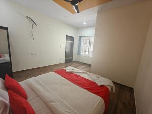 1 dormitorio con 1 cama grande con manta roja en The Whispering Willows, en Mysore