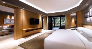 ein Schlafzimmer mit einem großen weißen Bett und einem TV in der Unterkunft Grand Hyatt Bali in Nusa Dua