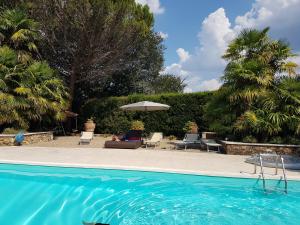 a swimming pool with chairs and an umbrella at Private Villa Dolce Vita in Lucignano