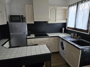 eine Küche mit weißen Schränken und einer Waschmaschine in der Unterkunft Maison Paris, Vallée Village, Disney & Astérix in Chelles