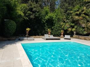 a blue swimming pool with two chairs and trees at Private Villa Dolce Vita in Lucignano +17 photos