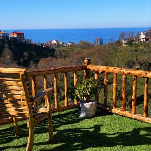 a wooden bench sitting on the grass near the ocean at Luna Bungalov in Rize