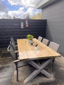 een houten tafel met stoelen en bloemen op een patio bij Etoile aan Zee in Vrouwenpolder