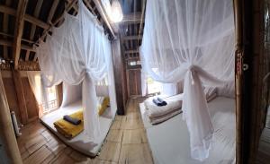 two beds in a room with white curtains at Muong Bi Homestay in Hòa Bình