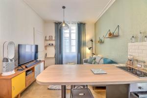 un salon avec une table et une télévision dans l'établissement Le Magdalena - Confort 4* en plein écusson, à Nîmes