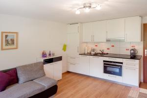 采尔马特阿尔贝斯根公寓的厨房配有白色橱柜和房间里的沙发