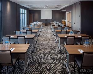 una sala de conferencias con mesas, sillas y una pantalla en Hyatt Place Harrisonburg en Harrisonburg