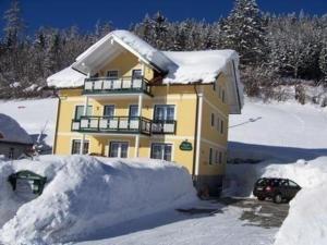 ein gelbes Haus mit einem Schneehaufen um ihn herum in der Unterkunft Tolle Wohnung in Zauchen mit Grill, Terrasse und Garten in Bad Mitterndorf