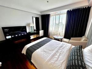 um quarto de hotel com uma cama grande e uma televisão em The Forest Lodge at Camp John Hay privately owned unit with parking 545 em Baguio