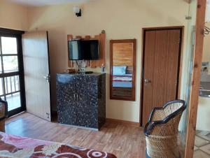 a living room with a television and a door with a chair at Khushi Cottage in Mukteswar