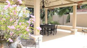 un patio con tavolo, sedie e fiori rosa di DUNEST VILLA a Bentota