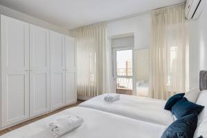 a white bedroom with two beds and a window at Modern Living in Kings Courtyard in Jerusalem
