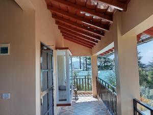 a porch of a house with a wooden ceiling at Khushi Cottage in Mukteswar