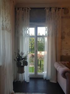 uma janela com cortinas brancas e um vaso de flores em Ehemalige Klosterschmiede -Wirtschaftswunder- em Ochsenhausen