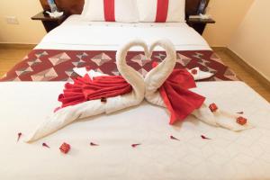 dwa łabędzie zrobione z ręczników na łóżku w obiekcie Africa One Hotel w mieście Naro Moru