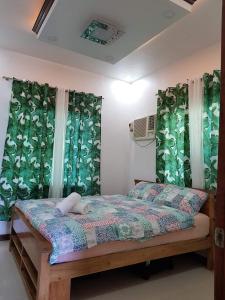 een slaapkamer met een bed met groene gordijnen bij Homaja Roomrental in Panglao