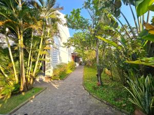 een bakstenen pad met palmbomen en een gebouw bij Hoian Village Lodge by Label6 in Hội An
