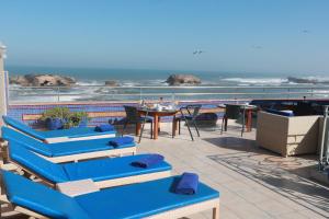 eine Terrasse mit blauen Stühlen, einem Tisch und Meerblick in der Unterkunft Riad Perle D'Eau in Essaouira