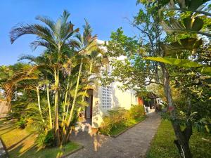 een gebouw met palmbomen ervoor bij Hoian Village Lodge by Label6 in Hội An