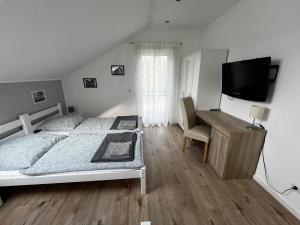 een slaapkamer met een bed, een bureau en een televisie bij HausGregor, Messe 15 min, City 20 min und Erholung im Grünen in Winkelhaid
