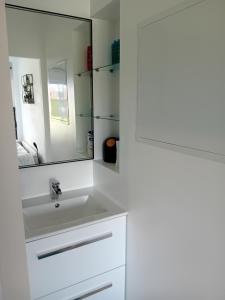 ein weißes Badezimmer mit einem Waschbecken und einem Spiegel in der Unterkunft Chez Maryline in Chalonnes-sur-Loire