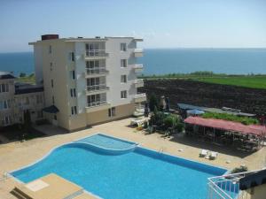 a large swimming pool next to a building and the ocean at Rutland Bay in Ravda