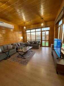 a living room with a couch and a table and a tv at اكواخ وشاليهات لوزان الريفية in Dahaban