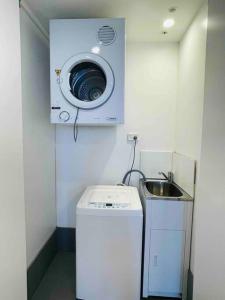 a washing machine in a small room with a sink at Stylish Apartment with city view close to beach airport cbd in Sydney