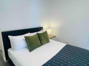 a bed with two green pillows on top of it at Stylish Apartment with city view close to beach airport cbd in Sydney