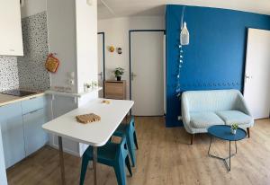 uma cozinha com uma mesa branca e uma parede azul em BELLE VUE OCEAN, 2 CHAMBRES, terrasse 30m2, parking privatif et piscine en été em Lacanau-Océan