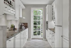 a kitchen with white cabinets and a large window at Nyere villa nær by, skov, strand in Højbjerg