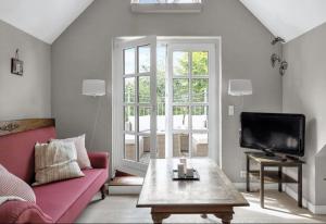 a living room with a pink couch and a tv at Nyere villa nær by, skov, strand in Højbjerg