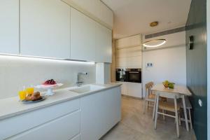 a kitchen with white cabinets and a table with a plate of food at City Lights 4 BR Stunning Apart in Jerusalem