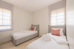 2 Betten in einem Zimmer mit weißen und rosa Kissen in der Unterkunft City Lights 4 BR Stunning Apart in Jerusalem