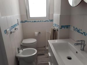a white bathroom with a toilet and a sink at Bellavista in Torre dell'Orso
