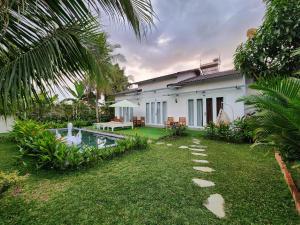 a house with a garden and a swimming pool at Ninila Fruit Farm Bungalow in Phu Quoc