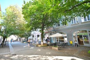 una calle de la ciudad con árboles y gente pasando por un edificio en MONTE Tu i Teraz, en Sopot