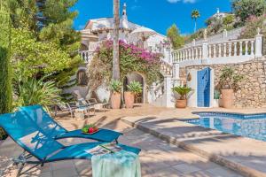 a blue chair in front of a house with a swimming pool at Villa Domingo - PlusHolidays in Benissa