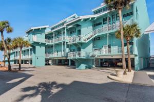 a blue building with palm trees in front of it at Palm Beach Club 3-235 in Pensacola Beach
