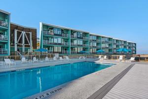 a hotel with a swimming pool with chairs and umbrellas at Palm Beach Club 3-235 in Pensacola Beach