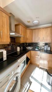 a large kitchen with wooden cabinets and a dishwasher at City Gem - Central & Stylish 1 Bed Apartment in Dublin
