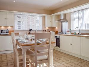 a kitchen with a wooden table and white cabinets at Lyncroft Holiday Bungalow in Sandbach