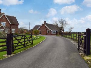 a road in a village with houses and a fence at Lyncroft Holiday Bungalow in Sandbach