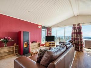 a living room with a leather couch and a tv at Oakwood Lodge in Lochwinnoch