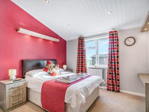 a bedroom with red walls and a bed and a clock at Oakwood Lodge in Lochwinnoch