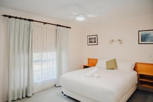 een slaapkamer met een wit bed en een raam bij Near Murray River - A Lovely Holiday Unit in Moama in Moama